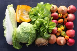 A selection of fresh vegetables, including lettuce, beets, and squash, arranged on a dark surface.